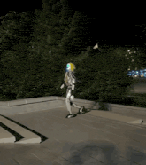 a robot is walking down a set of stairs with trees in the background