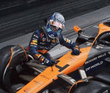 a man is sitting in a race car with a helmet on .