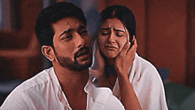 a man with a beard holds a woman 's face who is crying