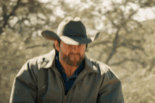 a man with a beard wearing a cowboy hat and a jacket