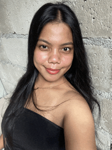 a woman with long black hair wearing a black off the shoulder top