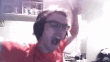a man wearing headphones and glasses is standing in front of a computer screen .