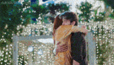 a man and a woman are hugging in front of a sign that says aaya-racha-me
