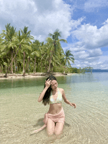 a woman in a bikini is kneeling in a body of water