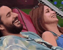 a man and a woman are laughing together while laying on a couch