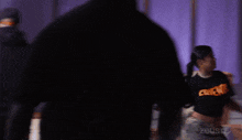 a blurry photo of a woman wearing a black shirt that says zeus on it