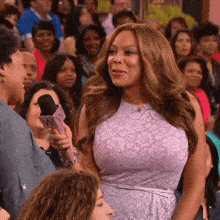 a woman in a purple lace dress is holding a microphone that says nn