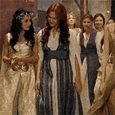a group of women in fancy dresses are standing next to each other in a room