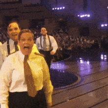 a group of people are standing on a stage with one woman screaming
