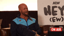 a man is sitting in front of a sign that says hey ( ew )