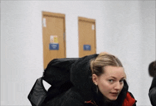 a woman wearing a black jacket is standing in front of two doors