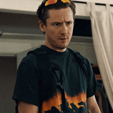 a man wearing sunglasses and a black t-shirt with a picture of a dinosaur on it
