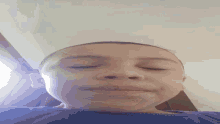 a young boy with his eyes closed and a blue shirt on