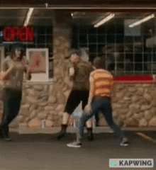 a group of people are dancing in front of a store with an open sign .