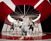 a group of young men are dancing in a circle on a red and white floor