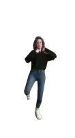 a woman in a black sweater and blue jeans is standing on one leg on a white background .