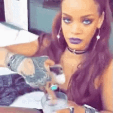 a woman is pouring a drink into a glass while wearing a choker and gloves .