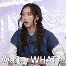 a woman is sitting in a chair with her mouth open and the words `` wait ... what ? '' written on the screen .