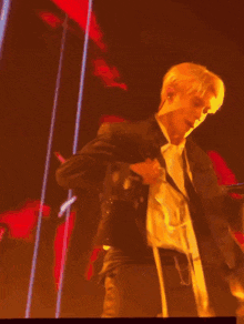 a man in a suit is dancing in front of a red curtain