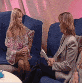 two women are sitting on a couch and talking to each other
