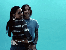 two women are standing next to each other on a blue background