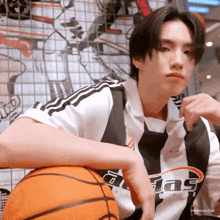 a man in an adidas shirt holds a basketball in his hand
