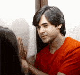 a man in a red shirt is touching another man 's hand