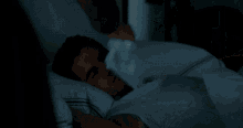 a man in a white shirt is laying in bed with white sheets