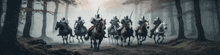 a group of knights are riding horses through a foggy forest