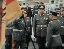 a group of men in military uniforms are standing in front of a flag that says " uni "