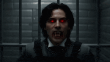 a man with vampire teeth and red eyes looks at the camera