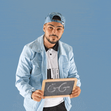 a man in a blue jacket is holding a chalkboard with the word gg written on it