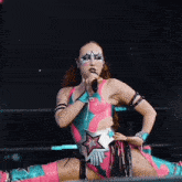a woman is singing into a microphone while wearing a pink and blue outfit