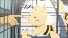 a teddy bear with a bee on it is in a cage and someone is pointing at it