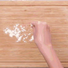 a ball of dough on a wooden cutting board with a rolling pin in the background