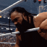 a wrestler with dreadlocks and a tattoo on his back is in a wrestling ring