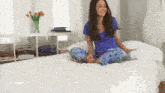 a woman sits on a bed with her legs crossed
