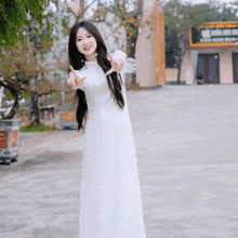 a woman in a white dress is standing in front of a building that says ' saigon ' on it