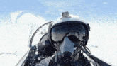 a man wearing a helmet and goggles looks out the window of a plane