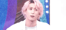 a young man with pink hair is making a funny face while wearing a white shirt and a white jacket .