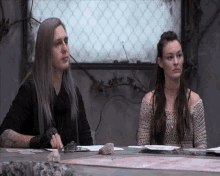 a man and a woman are sitting at a table looking at something .