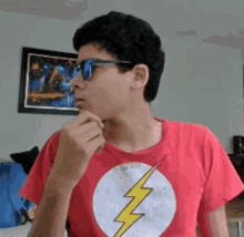 a young boy wearing sunglasses and a red shirt with a lightning bolt on it