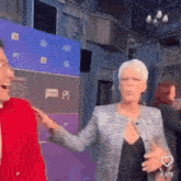 a woman in a gray jacket is pointing at a man in a red jacket