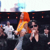 a man is singing into a microphone while a woman stands behind him