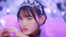 a girl wearing a tiara and a purple dress looks at the camera