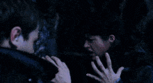 a man is looking at a woman 's hand that is glowing blue
