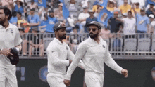 a group of cricket players are walking across a field holding hands .