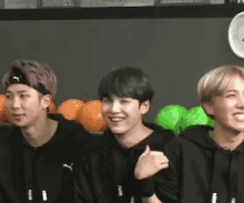 a group of young men are sitting next to each other in front of a fruit stand and smiling .