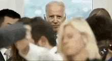 a blurry picture of a man in a suit and tie surrounded by people .