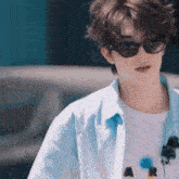 a young man wearing sunglasses and a blue shirt is walking down a street .